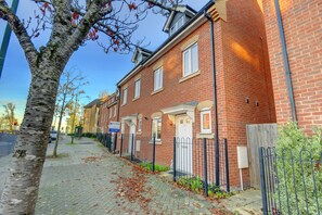 Charming townhouses with gardens and white-framed windows line the sidewalk.