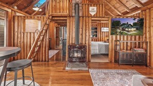 A rustic cabin interior with a wooden interior, a fireplace, a dining area, and a view of the cabin outside. - Lakefront Log Cabin-Stunning Lake Views, Kayaks, Steps to Beach & dt Lake City! (Lake City)
