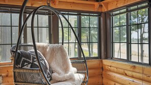 A log cabin interior with a hanging chair by a large window. - Lakefront Log Cabin-Stunning Lake Views, Kayaks, Steps to Beach & dt Lake City! (Lake City)
