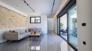 A modern living room with a stone wall, a sofa set, a coffee table, and a large sliding glass door leading to an outdoor area.
