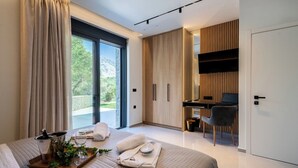 A modern bedroom with a large bed, a desk, and a view of a mountainous landscape.