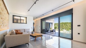 A modern living room with a sofa, coffee table, and a view of a balcony with outdoor seating.
