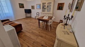 Un salon avec un plancher en bois, une table à manger avec des chaises, un canapé, un téléviseur et un meuble.