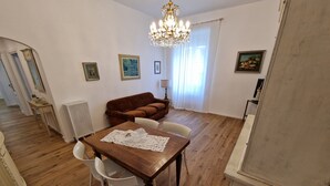 Un coin repas avec une table en bois et des chaises blanches, un canapé marron et un lustre.