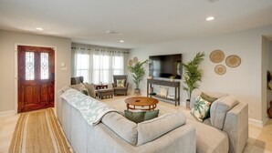 A living room with a sectional sofa, a round coffee table, a TV, and a fireplace. - Luxe San Antonio Vacation Rental w/ Private Pool! (San Antonio)