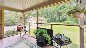 A covered porch with a grill, a chair, a table, and hanging flower baskets. - Greensboro Golf Getaway - 9 Mi to Downtown! (Greensboro)