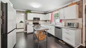 A modern kitchen with white cabinets, stainless steel appliances, and a central island. - Greensboro Golf Getaway - 9 Mi to Downtown! (Greensboro)