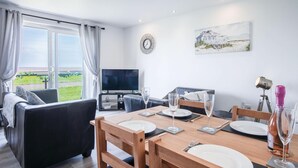 Ein modernes Wohnzimmer mit Essbereich, Fernseher und einem Gemälde an der Wand.