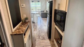 Una cucina angusta con forno a microonde, frigorifero e un piccolo spazio pranzo visibile sullo sfondo.