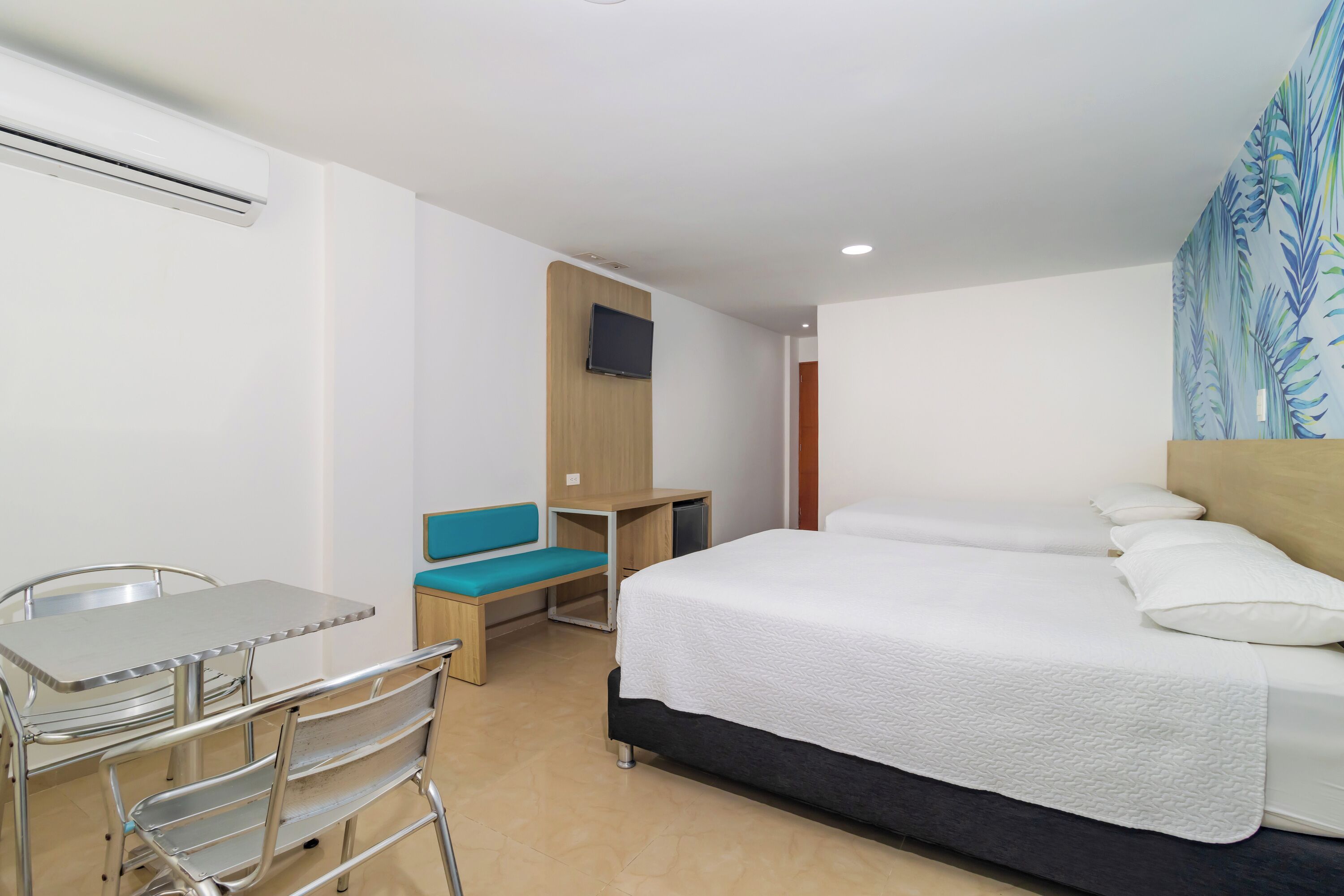 Habitación de hotel con cama, escritorio, silla, televisión y ventana con vistas.
