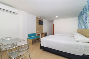 Habitación de hotel con cama, escritorio, silla, televisión y ventana con vistas.
