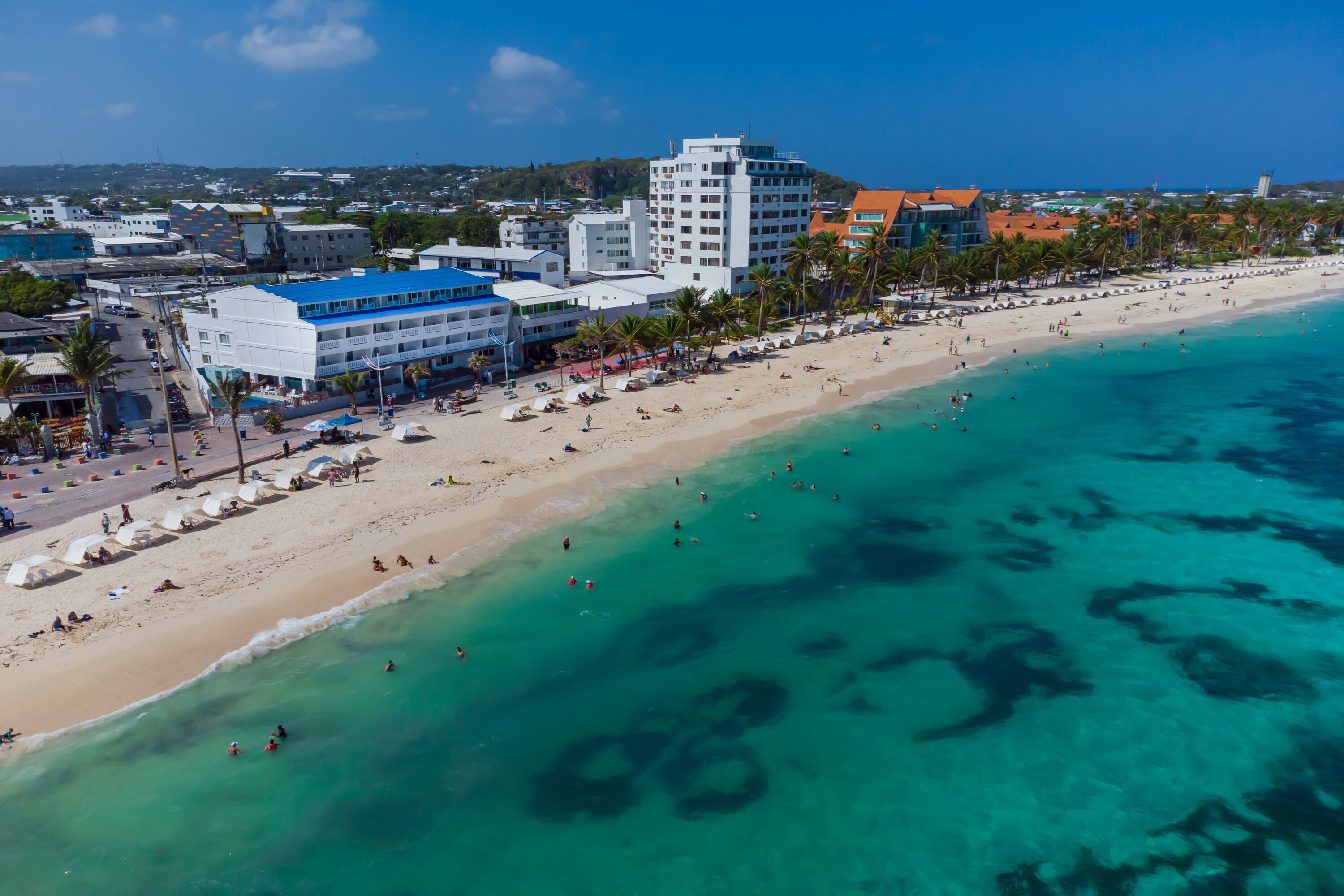 A coastal hotel with multiple floors, a beachside location, and a view of the ocean.