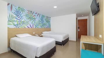 Quarto de hotel com duas camas, cabeceira de madeira, painel na parede, televisão fixada na parede e uma mesinha.