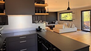 Una cucina moderna con mobili neri, un'isola centrale e un'area pranzo con divano e sedie.