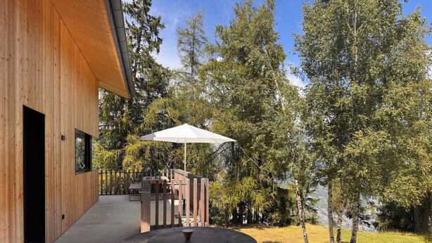 Un edificio in legno con patio, posti a sedere all'aperto e un grande ombrellone.