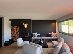 Un salon moderne doté d’une cheminée, d’un coin salon et d’une grande fenêtre.
