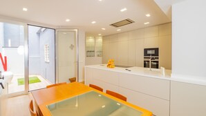 Une cuisine moderne avec une table à manger au plateau en verre, des meubles de rangement blancs et un four encastré.
