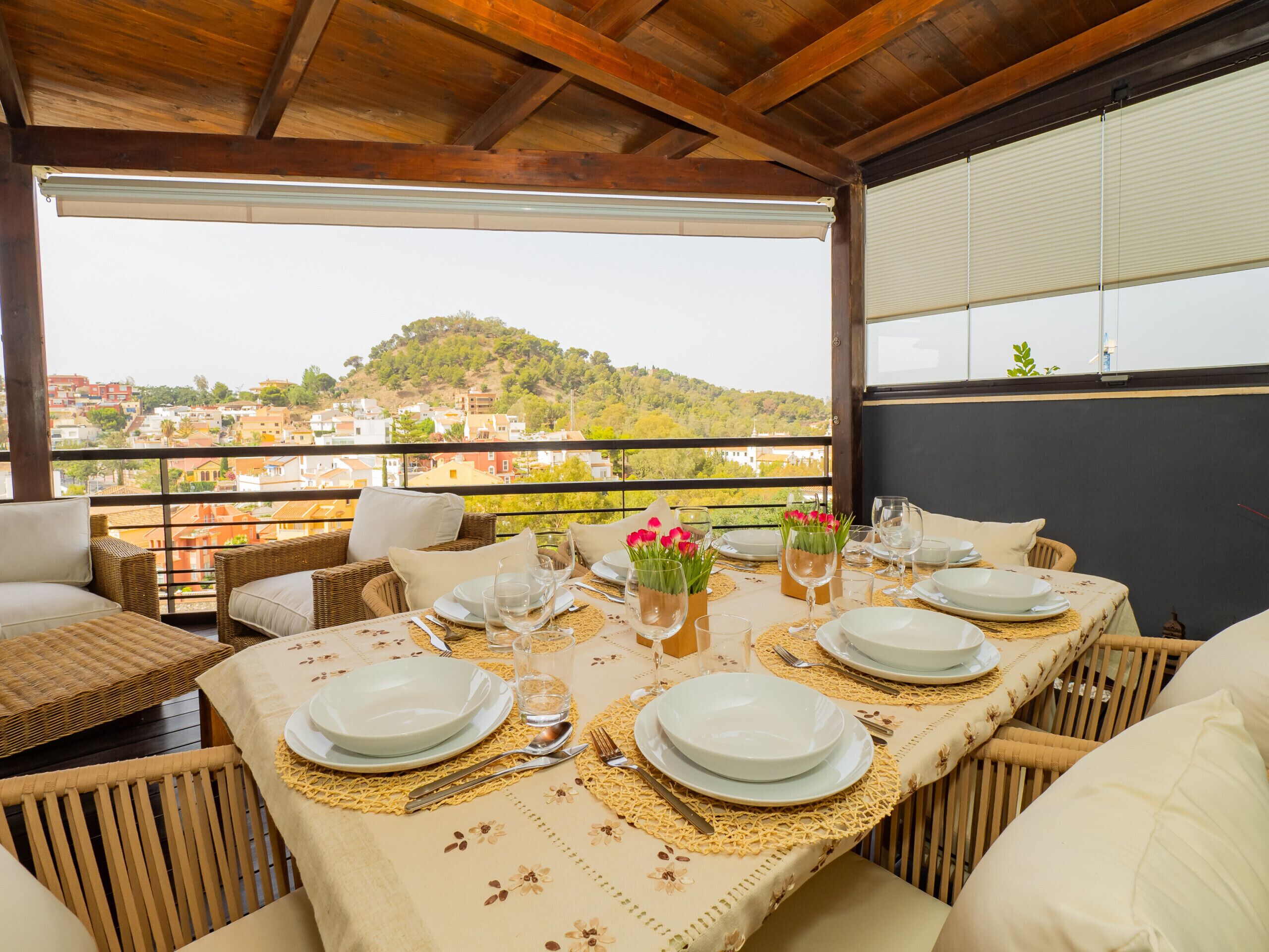 A dining area with a table set for four, overlooking a hillside town.