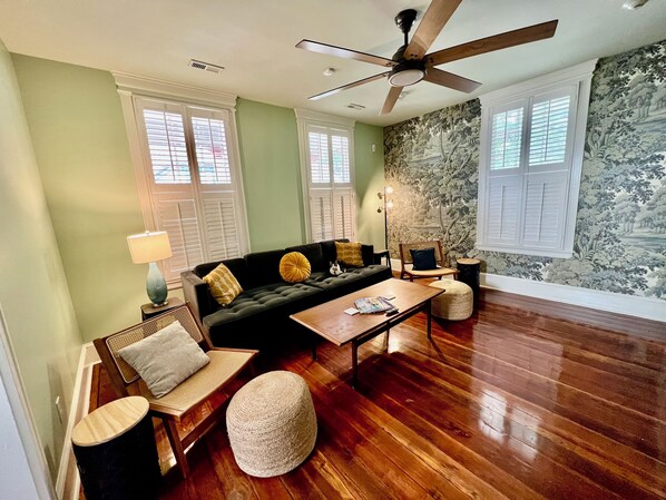 A living room with a dark green sofa, wooden coffee table, and a ceiling fan. - Downtown Macon Cottage Walking Distance to Dining & Music Venues. 2 King Beds. (Macon)