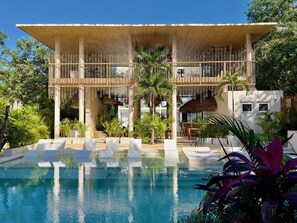 A resort with a pool, lounge chairs, and a covered outdoor area with bamboo structures. - Jungle Studios in Tulum by Casago (Tulum)
