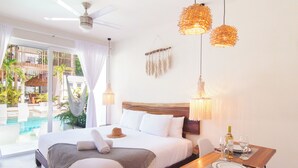 Un dormitorio con una cama, una mesa de comedor con platos y vasos, un ventilador de techo y vista a una piscina y zona exterior.