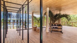 Un espacio interior amplio con piso de madera, vigas de metal y ventanas grandes.