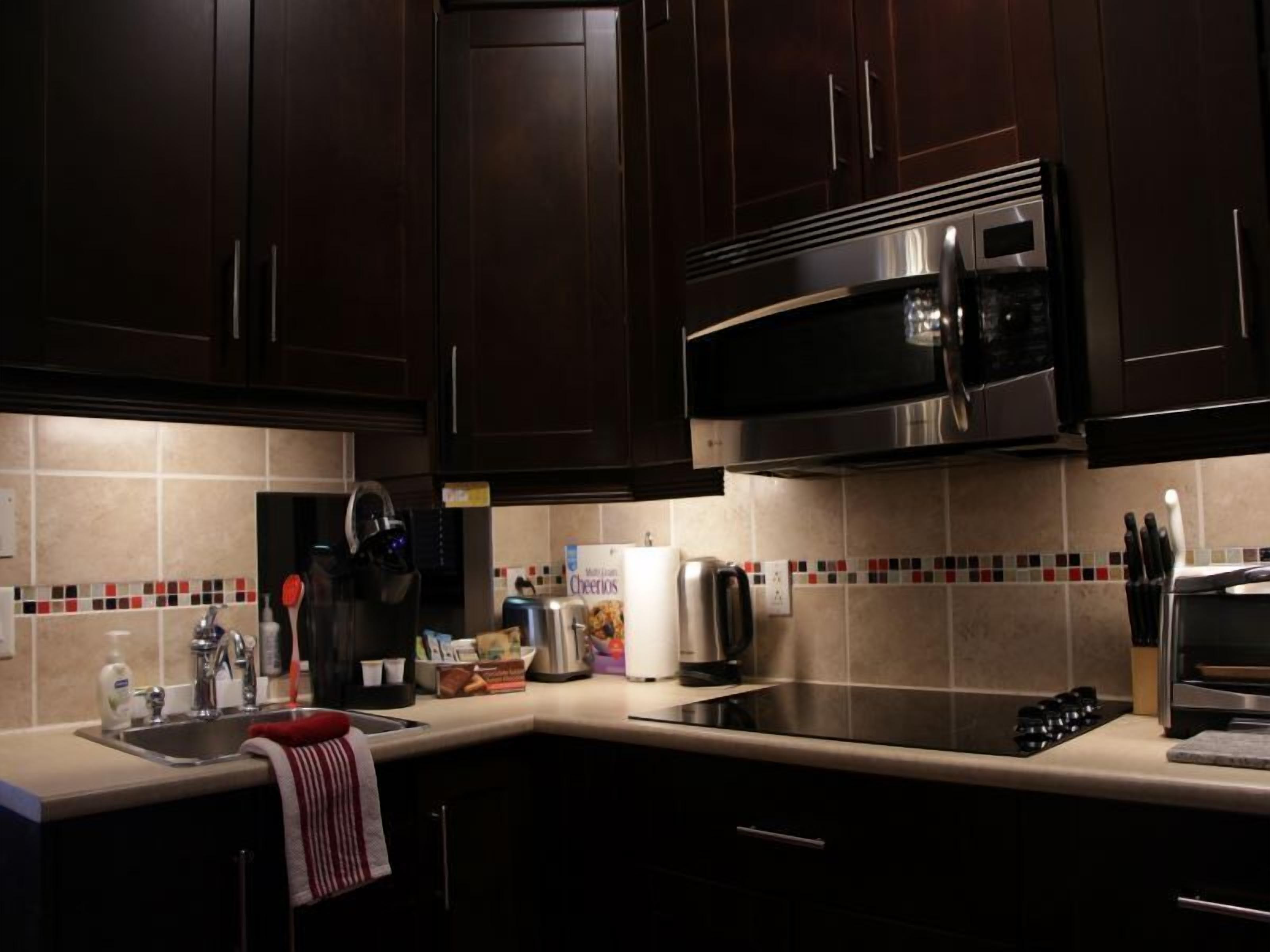 A modern kitchen with dark wooden cabinets, stainless steel appliances, and a tiled backsplash.