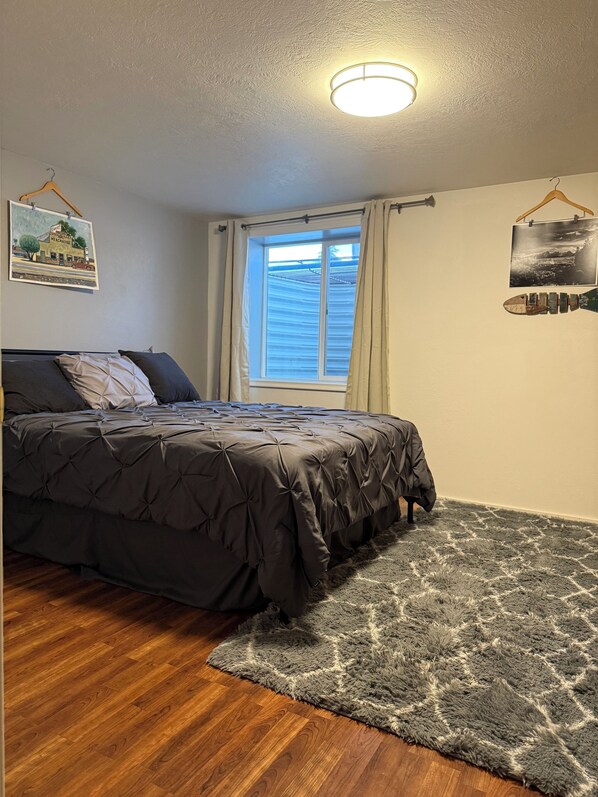 Une chambre à coucher avec un lit, une fenêtre, un luminaire au plafond et un tapis.