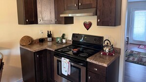 A kitchen with dark wood cabinets, a stainless steel stove, and a heart-shaped decoration on the wall.