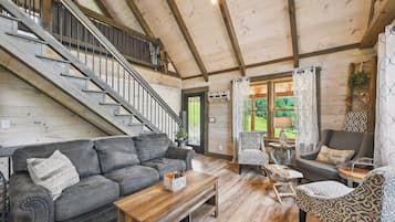 Un vaste espace de vie comprenant un escalier, des planchers en bois et un mélange de meubles modernes et classiques.