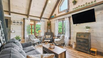 Un salon chaleureux avec un plafond en bois, une grande télévision et une cheminée.