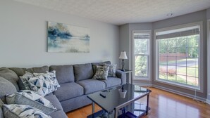 Ein Wohnzimmer mit einem grauen Sofa, einem Glastisch und einem Bild an der Wand.