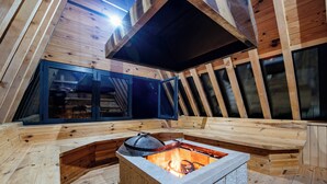 Un dormitorio en el ático con chimenea de piedra, vigas de madera y ventanas grandes.