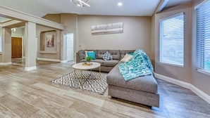 A spacious living room with a sectional sofa, a coffee table, and a patterned rug.