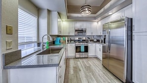 A modern kitchen with white cabinets, stainless steel appliances, and a granite countertop.