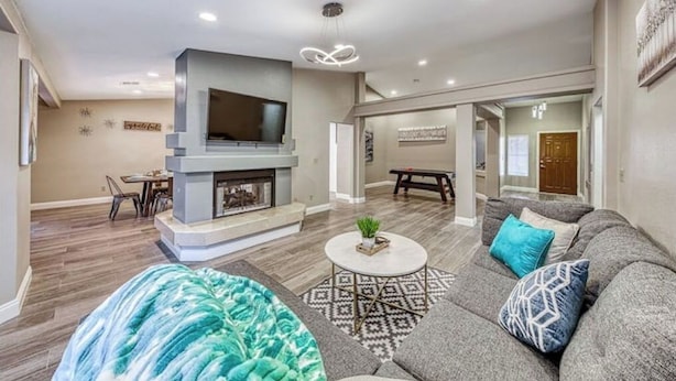 A modern living room with a fireplace, a sofa, a coffee table, and a TV mounted on the wall.