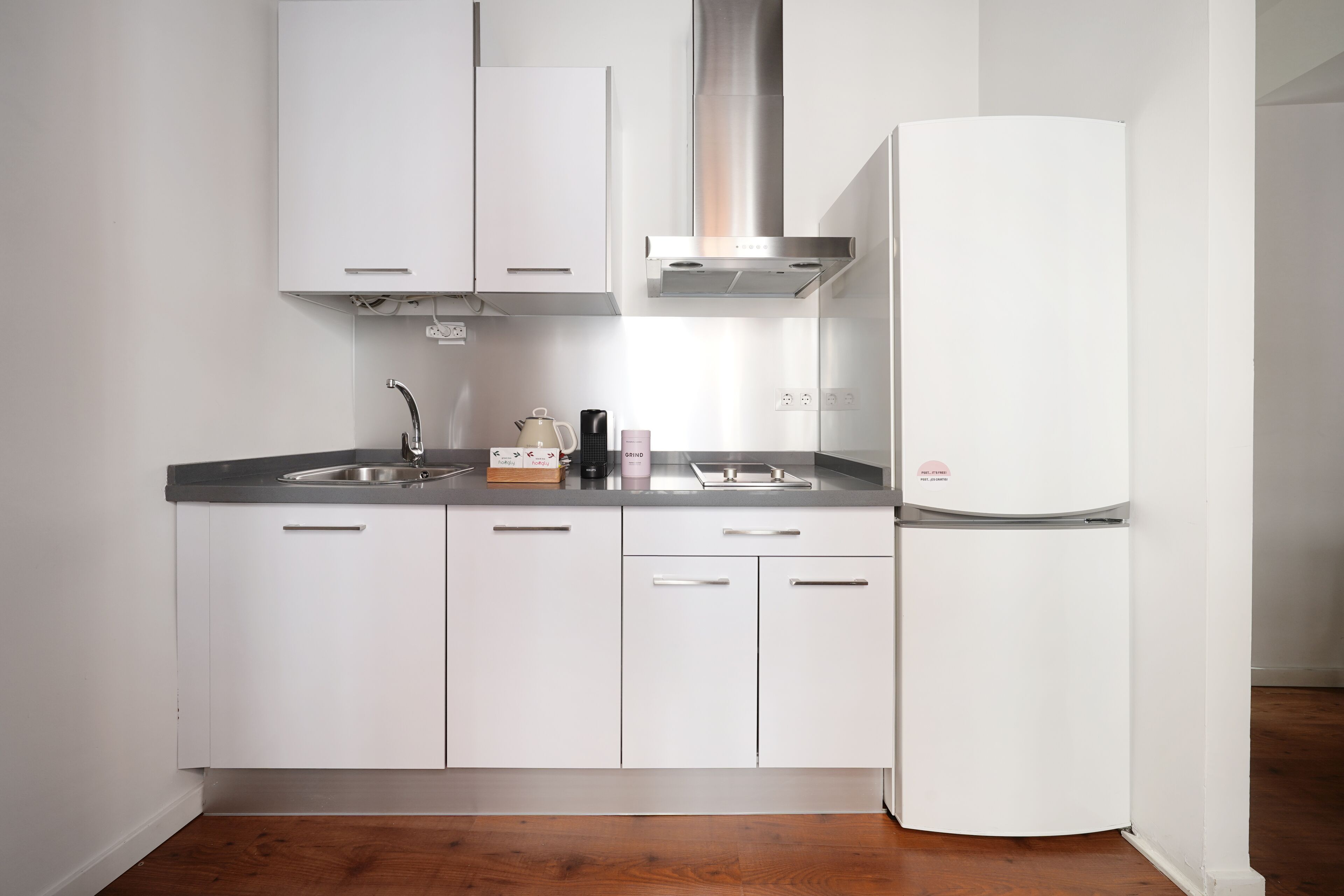 A modern kitchen with white cabinets, a stainless steel sink, and a built-in oven.