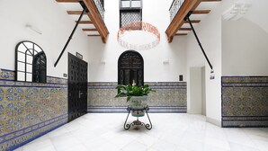 A spacious hallway with patterned tile walls, a potted plant, and a black door. - Numa Seville Alegre (Seville)