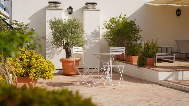 A patio with a white table and chairs, potted plants, and a tiled floor. - Numa Seville Alegre (Seville)