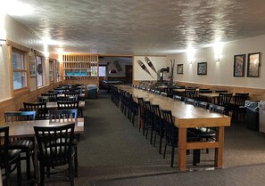 Dining area with tables and chairs, adorned with artwork and featuring a textured ceiling.