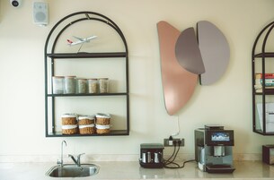 Una cocina con una repisa empotrada que contiene frascos, una cafetera y un altavoz de pared.