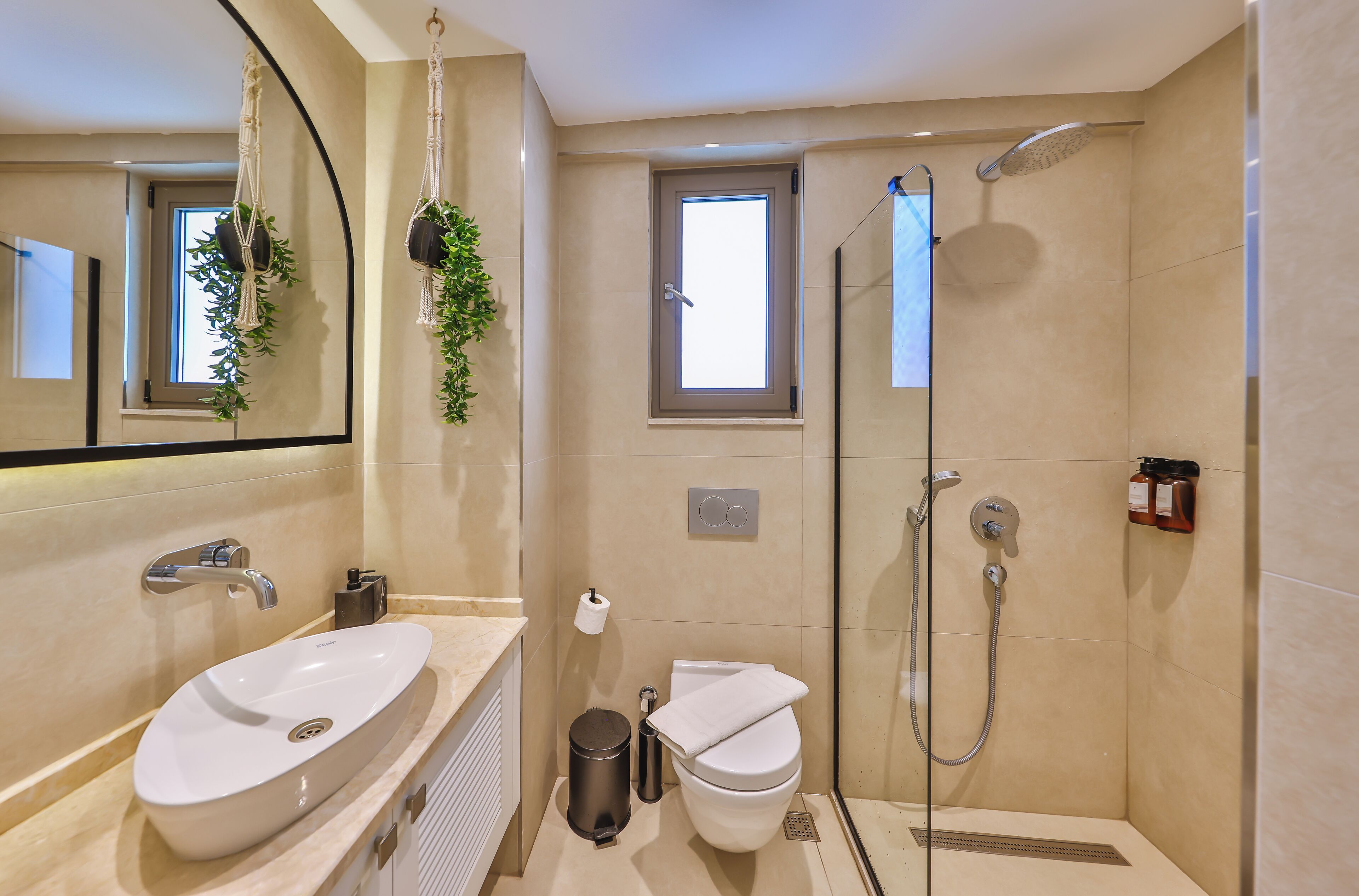 A modern bathroom with a large mirror, a sink, a toilet, and a shower.
