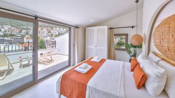 Habitación de hotel con balcón, cama con ropa de cama blanca y naranja, un ventanal grande y vistas a la ciudad.