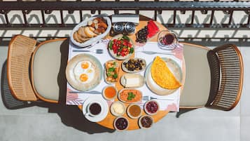 Una mesa dispuesta con diversos alimentos y bebidas, como huevos, pan, aceitunas y una rebanada de sandía.