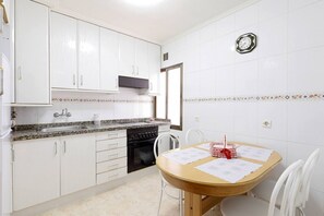 A kitchen with white cabinets, a granite countertop, a stove, and a dining table with chairs. - 621B Cozy Apartment by R2R Consulting (Oviedo)