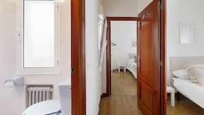Een gang die leidt naar een slaapkamer met een houten deur, een wit toilet en een radiator.