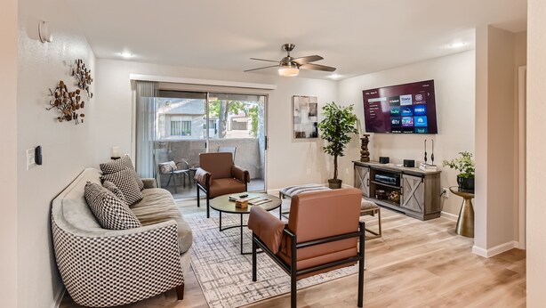 Una sala de estar moderna con un sofá, sillones, una mesa de centro y un televisor.