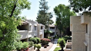 Un complejo residencial con varias edificaciones de dos pisos, un camino central y jardines ajardinados.