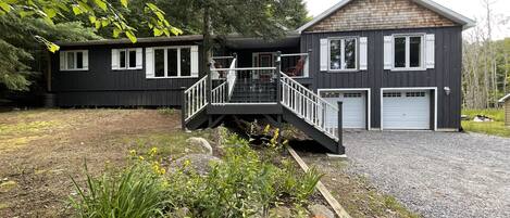 Et toetagers hus med en overdækket veranda, garage og en grusvej.