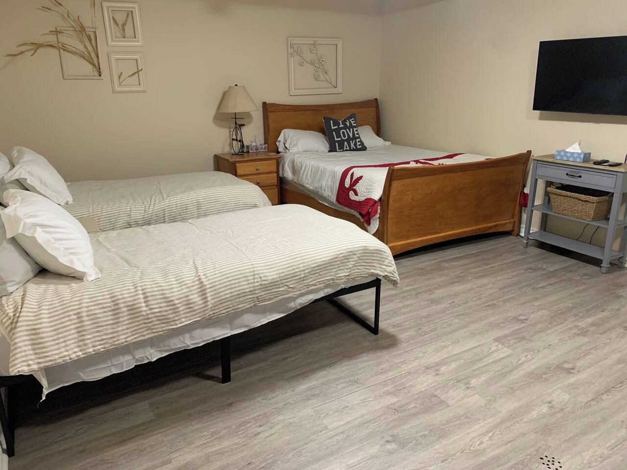 A hotel room with two single beds, a wooden nightstand, a desk with a chair, and a television on the wall.